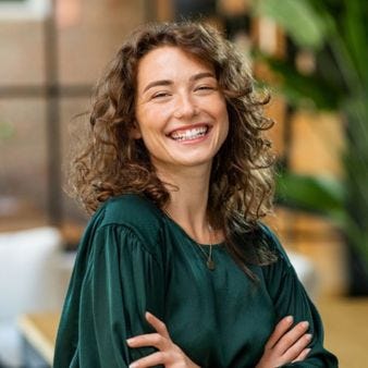 Junge Frau mit dunklen Locken lacht in die Kamera