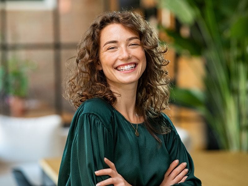 Junge Frau mit dunklen Locken lacht in die Kamera