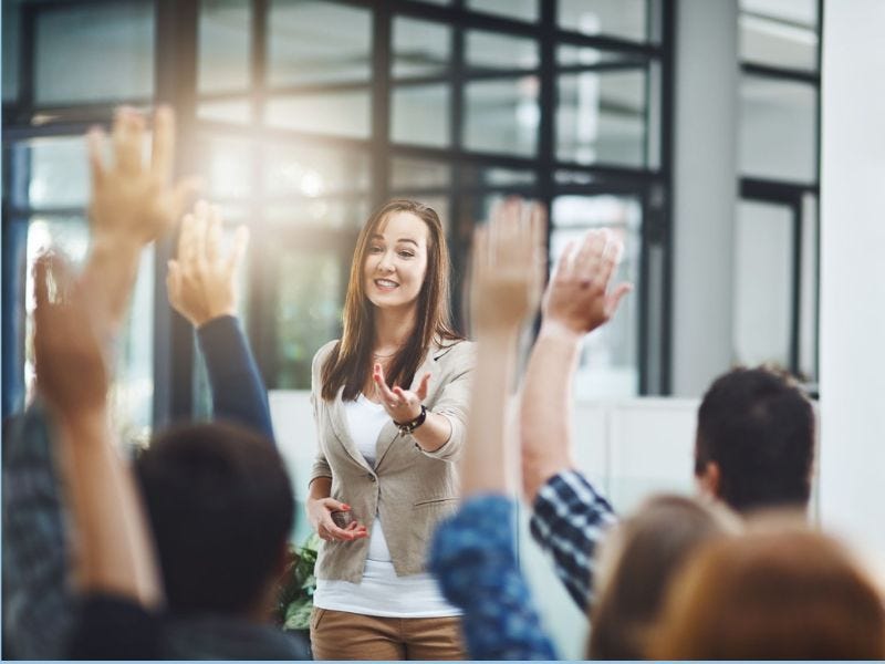 Business Frau steht vor Gruppe, die sitzen und sich melden.