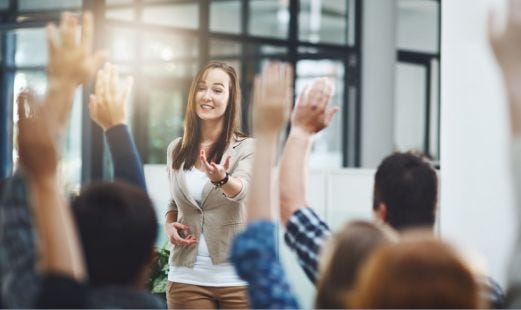 Business Frau steht vor Gruppe, die sitzen und sich melden.