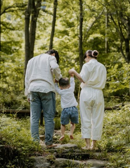 Familie mit Kind an der Hand stehen im Wald