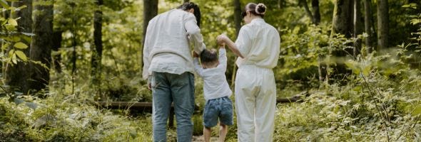 Familie mit Kind an der Hand stehen im Wald