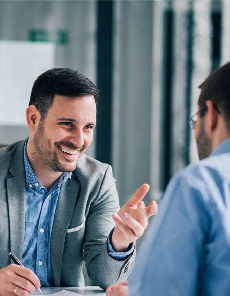 Zwei Männer führen in einem Büro lächelnd ein persönliches Gespräch.