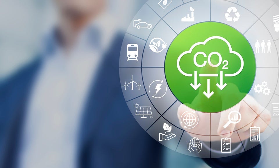 Geschäftsperson im Hintergrund, vorne eine kreisförmige Grafik mit Symbolen zu Energie und Umwelt; in der Mitte ein grünes Icon mit CO₂-Wolke und Pfeilen nach unten, das CO₂-Reduzierung darstellt.