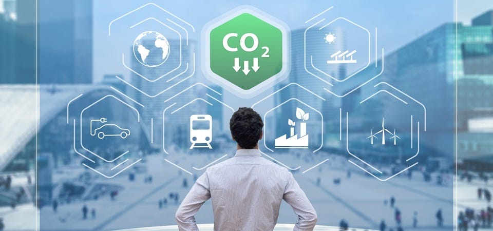 Eine Person blickt auf eine Stadt. Darüber schweben Symbole für Nachhaltigkeit und CO₂-Reduktion wie Windräder, E-Autos und Solarenergie.