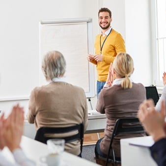 Ein Mann referiert vor einer Seminarteilnehmergruppe.