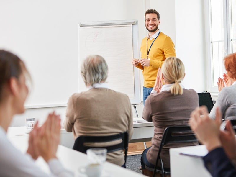Ein Mann referiert vor einer Seminarteilnehmergruppe.