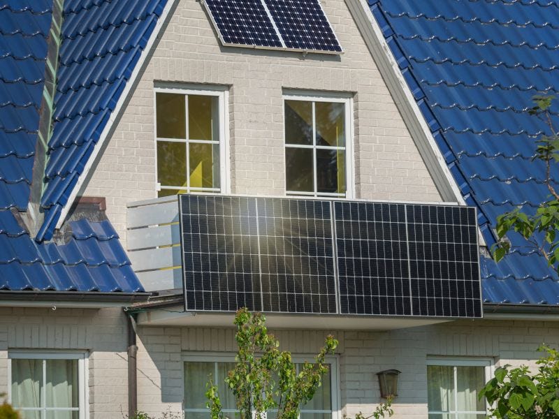 Ein Balkon an einem Haus, an dem Solarpanele montiert sind. Die Sonne scheint drauf.