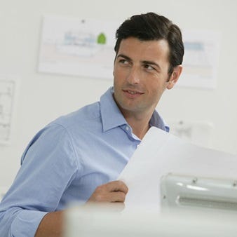 Konzentrierter Mitarbeiter mit Bauplänen im Büro