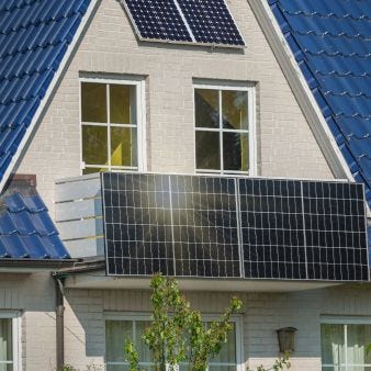 Das Bild zeigt ein Haus mit installierten Solarpaneelen auf dem Dach und an der Fassade. Die Solarpaneele sind so positioniert, dass sie das maximale Sonnenlicht einfangen, um nachhaltige Energie zu erzeugen. 