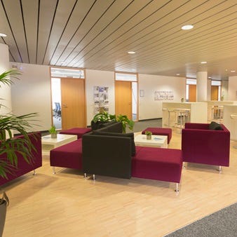 Modulare Magenta-Sitzm&ouml;bel und schwarze Elemente mit wei&szlig;en Beistelltischen und gr&uuml;nen Pflanzen in B&uuml;rolounge