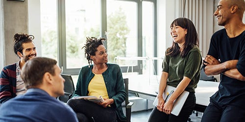 Mehrere Mitarbeitende diskutieren gemeinsam in einem modernen B&uuml;ro und tauschen sich zu Prozessen und Verbesserungen aus.