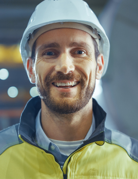 Person in Schutzhelm und Warnkleidung in Produktionsumgebung