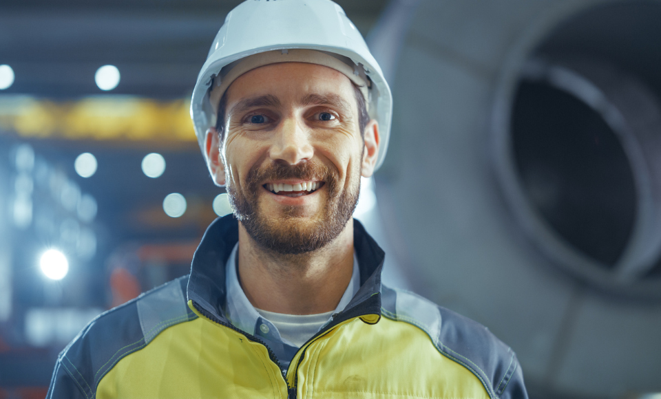 Person in Schutzhelm und Warnkleidung in Produktionsumgebung