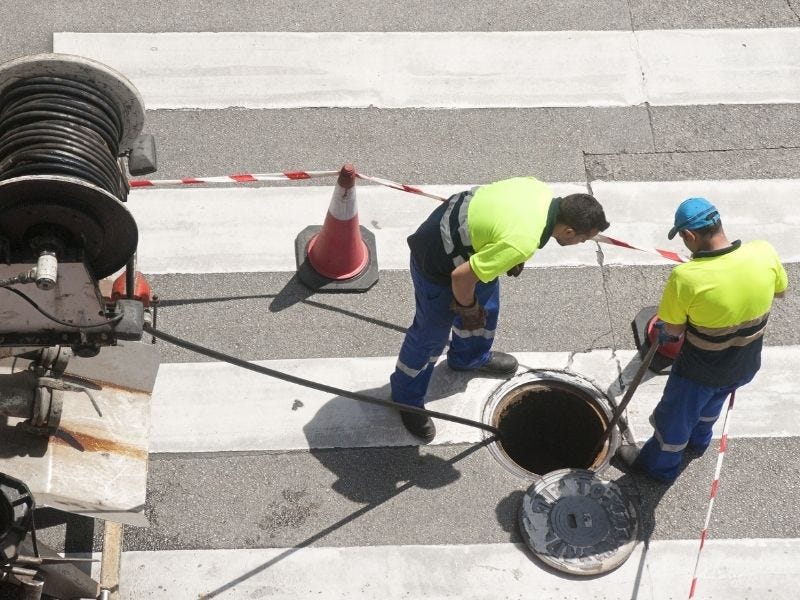 Zwei Männer haben eine Baustelle auf der Straße abgesperrt.