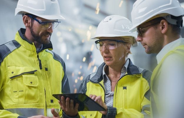 Eine Arbeitsschutzbeauftragte unterh&auml;lt sich mit zwei Kollegen 