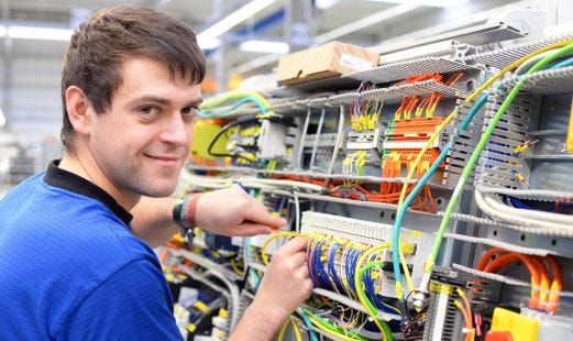Mann bei Elektroarbeiten schaut in die Kamera und lächelt.