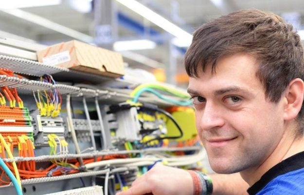 Elektriker bei der Arbeit und l&auml;chelt in die Kamera