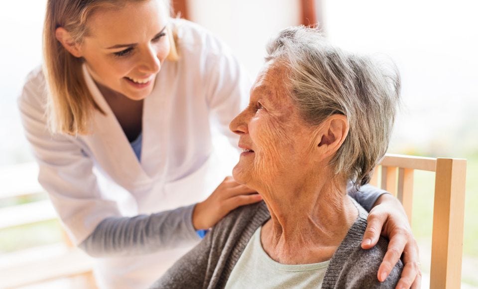 Weibliche Pflegekraft lächelt ältere Patientin an