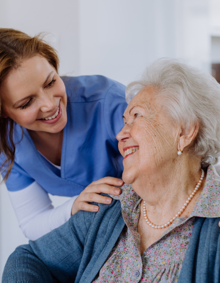 Eine Pflegekraft lächelt eine Patientin an.