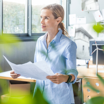 Frau hält einen Plan in der Hand um sie herum sind Pflanzen
