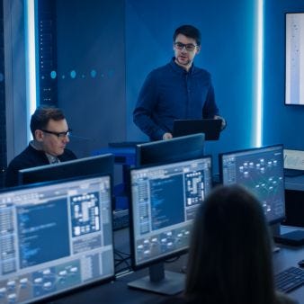Computerraum mit mehreren Menschen die vor den Monitoren sitzen