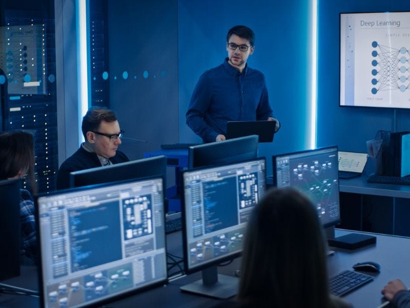 Computerraum mit mehreren Menschen die vor den Monitoren sitzen