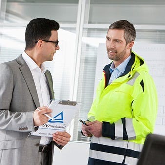 2 Männer einer mit einem Klemmbrett in der Hand unterhalten sich
