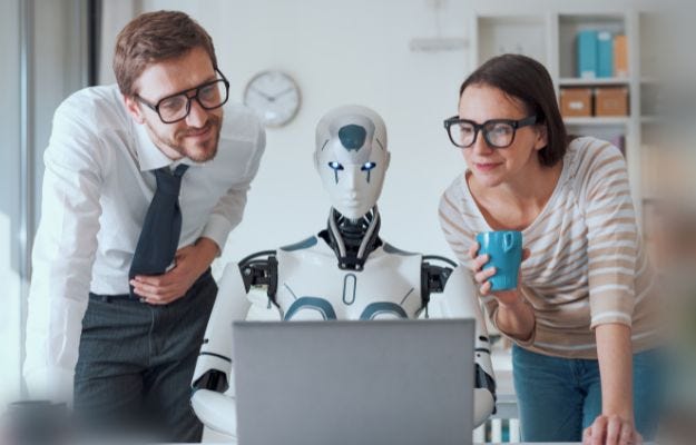 Eine Frau und ein Mann stehen neben einem Roboter der ein Notebook bedient