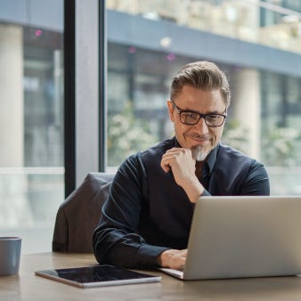 Lächelnde Person im Büro schaut auf Laptop