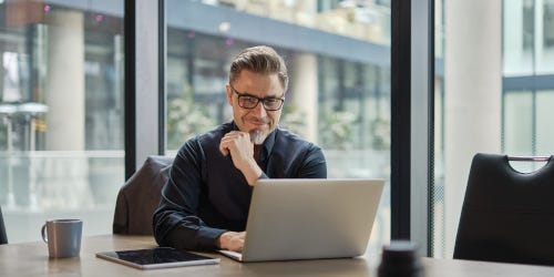 Lächelnde Person im Büro schaut auf Laptop