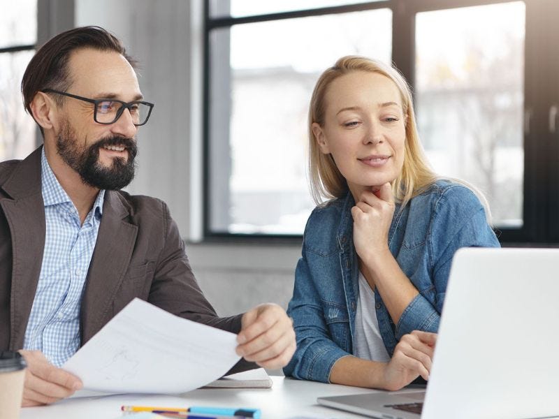 betriebliches Gesundheitsmanagement? Mann und Frau sitzen nebeneinander und gucken auf Laptop