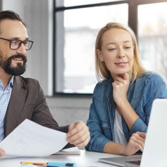 betriebliches Gesundheitsmanagement? Mann und Frau sitzen nebeneinander und gucken auf Laptop