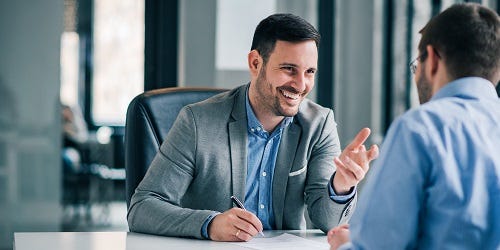 2 Männer unterhalten sich am Schreibtisch im Büro