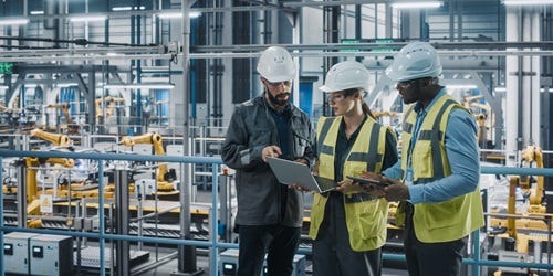 Junges Team von Spezialisten in einer Autofabrik arbeitet mit Laptop- und Tablet-Computern.