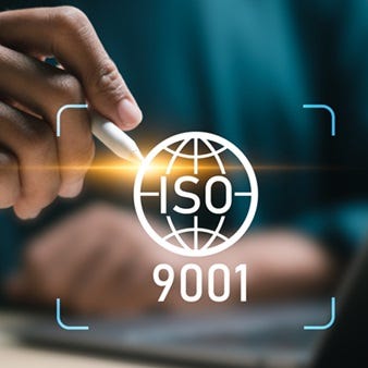 Eine Hand mit Stift zeigt auf ein digital erstelltes Symbol mit "ISO 9001" Schriftzug.