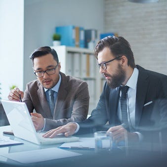 Zwei Männer sitzen am Schreibtisch und schauen auf einen Bildschirm