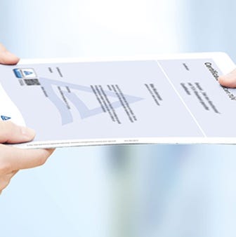 Zwei H&auml;nde &uuml;berreichen ein Zertifikat mit T&Uuml;V- Logo vor unscharfem, hellem Hintergrund.