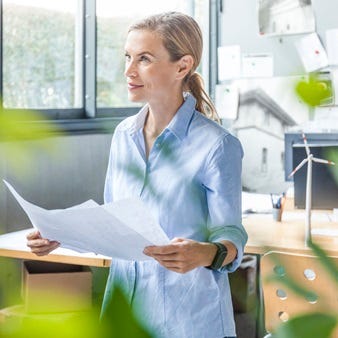 Frau in einem Büro mit Dokumenten in der Hand