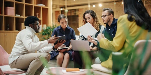 Diverse Gruppe von Menschen im Meeting diskutiert gemeinsam Ideen in modernem B&uuml;ro.