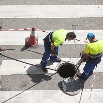Zwei Männer haben eine Baustelle auf der Straße abgesperrt.