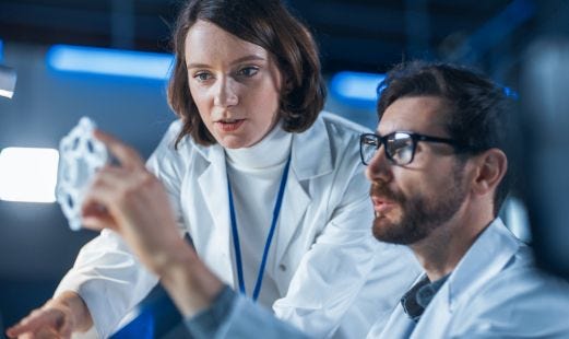 Frau und Mann in weißen Kitteln arbeiten gemeinsam an einem Schreibtisch